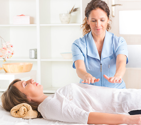 Mujer aplicando reiki a un paciente